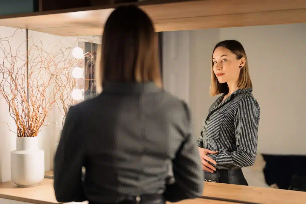 Lovely woman looking at her reflection in the mirror